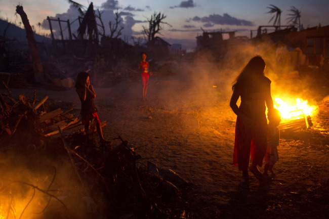 Typhoon Haiyan survivors walk past open fires, set to remove debris from the ruins of the village of Marabut, Samar Island, Philippines, Friday. (AP-Yonhap News)