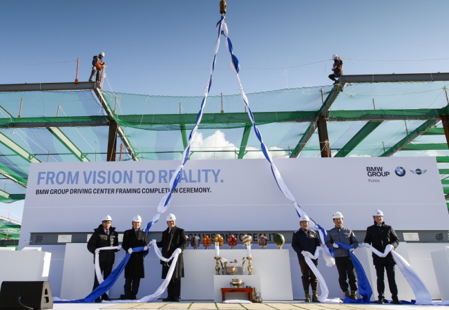 BMW Korea CEO Kim Hyo-joon (third from left) and other company officials celebrate the completion of the frame for a BMW driving center ― first outside of Germany and the U.S. ― during an event at the construction site on Yeongjongdo Island, Incheon, Tuesday. (BMW Korea)