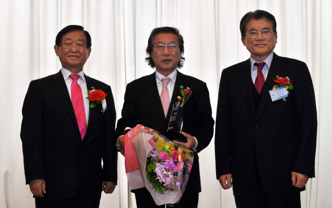 Herald Corp. CEO and publisher Lee Young-man (center) poses after receiving an achievement award from the Korean Society of Olympic Flame in Seoul Olympic Parktel on Friday. He is flanked by former presidents of the society Chung Tong-gu (right) and Chung Chung-hee.  (Lee Sang-sub/The Korea Herald)