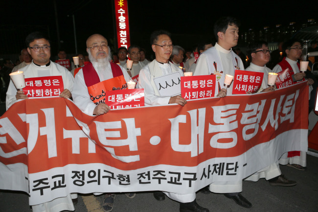 천주교정의구현사제단 전주교구 사제들이 22일 오후 전북 군산시 수송동성당에서 `불법 선거 규탄과 대통령 사퇴를 촉구하는 시국미사`를 봉헌한 뒤 인근 대형마트까지 촛불을 들고 행진하고 있다. (연합뉴스)