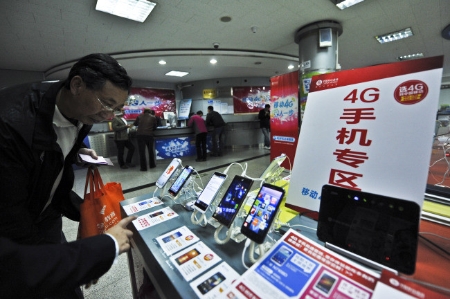 A staff member introduces the service of 4G mobile network to a customer in Beijing, China. (Xinhua-Yonhap News0