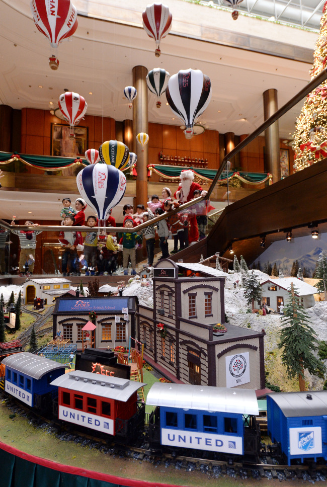 Children and hotel staff dressed in festive holiday attire look at the newly installed Christmas train at the Millennium Seoul Hilton on Wednesday. The annual Christmas train, which has been installed at the hotel for 18 consecutive years, will run until Feb. 2. Donations from more than 60 companies that have sponsored the display have also been collected and sent to social welfare facilities. (Ahn Hoon/The Korea Herald)