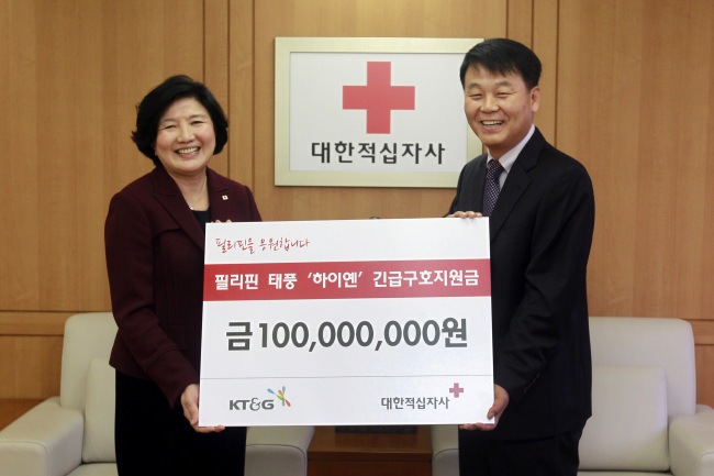 Kim Tae-sub (right), managing director and head of KT&G’s sustainability management office, delivers 100 million won ($94,300) from the tobacco and ginseng corporation to Yu Jung-keun, president of the Korean Red Cross, for relief aid to the typhoon-devastated Philippines at the Red Cross in Seoul on Wednesday. (KT&G)