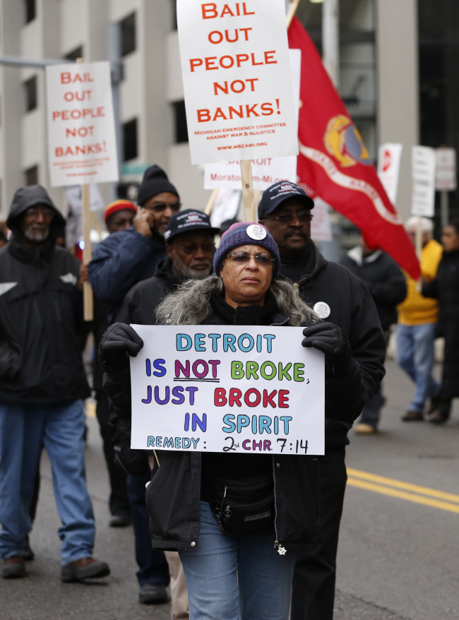 Protesters hold signs as they march outside the Theodore Levin U.S. Courthouse in Detroit, Michigan, Tuesday. (Bloomberg)