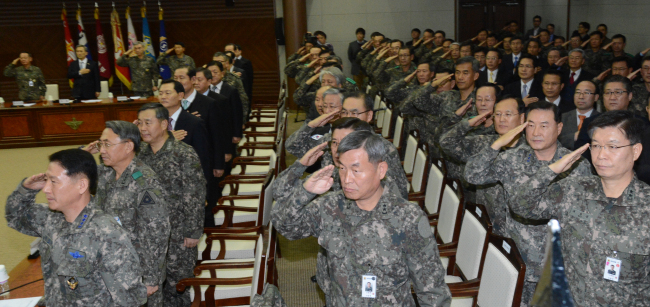 Defense Minister Kim Kwan-jin (second from left, at rear) and top military commanders salute the national flag on Wednesday at the Ministry of Defense ahead of a semiannual commanders’ meeting.(Chung Hee-cho/The Korea Herald.)