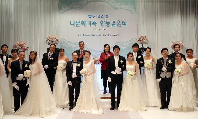 Woori Financial Group chairman Lee Soon-woo (left, back row) applauds after conducting a group wedding of 10 multicultural couples at the group headquarters in central Seoul, Saturday. The event was hosted by the Woori Multicultural Scholarship Foundation and supported by Seoul City for multicultural couples who did not have a wedding ceremony due to economic and other personal reasons. (Woori Financial)