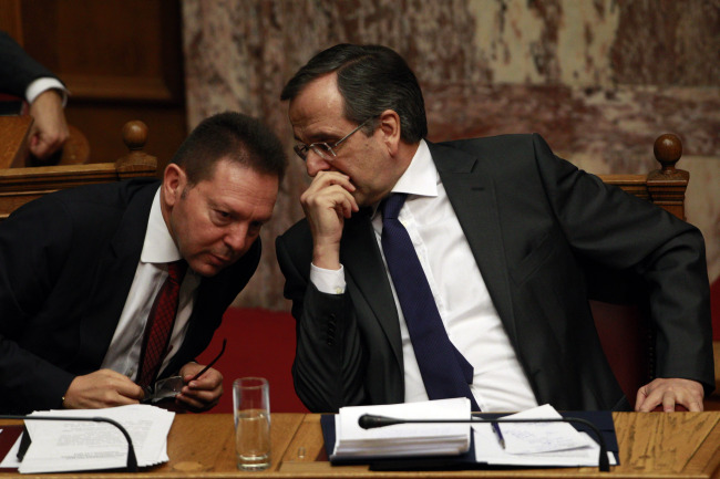 Greek Prime Minister Antonis Samaras (right) talks to Finance Minister Yannis Stournaras during a parliament meeting for a vote on the 2014 budget in Athens on Saturday.  (AP-Yonhap News)