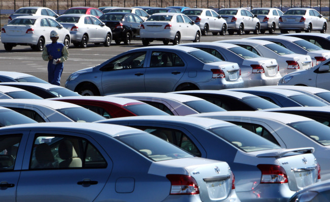 An employee passes Yaris automobiles manufactured by Toyota Motor Corp. and awaiting shipment at the Central Motor Co.’s Miyagi plant in Ohira Village, Miyagi prefecture, Japan. (Bloomberg)