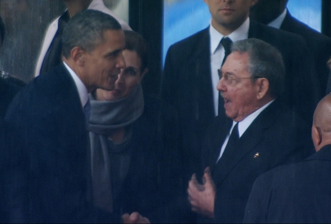 In this image from TV, US President Barack Obama shakes hands with Cuban President Raul Castro at the FNB Stadium in Soweto, South Africa, in the rain for a memorial service for former South African President Nelson Mandela, Tuesday. (AP-Yonhap news)