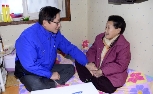 Samsung C&T president and CEO Kim Shin delivers gifts and household supplies to 80-year-old Kim Ok-ji as part of the company’s community service for residents of tiny flophouses in Seoul on Wednesday. (Park Hae-mook/The Korea Herald)