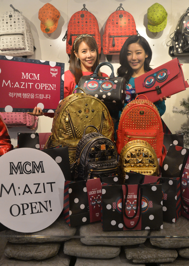 Sales clerks promote a sales event for M:AZIT, a store opened by MCM, a luxury German leather brand, in Seoul on Thursday. To celebrate its opening, the store will sell a dozen randomly selected MCM items originally priced between 600,000 and 2 million won for 120,000 won each day on a first come, first served basis until Jan. 24.(Lee Sang-sub/The Korea Herald)