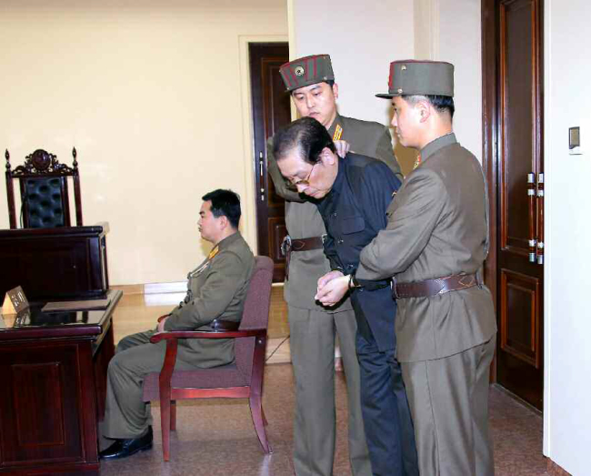 A photograph from North Korea’s Rodong Sinmun shows Jang Song-thaek (center) in handcuffs as he is escorted by military officers to his trial on Thursday. (Yonhap News)