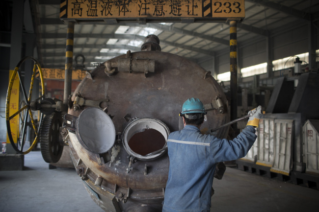 An employee cleans aluminum residue from a container at the China Hongqiao Group Ltd. aluminum smelting facility in Zouping, China. (Bloomberg)