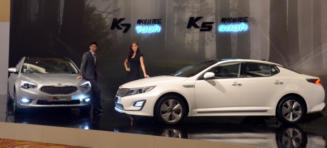 Kia Motors unveils hybrid versions of its flagship K5 (right) and K7 sedans, named 500h and 700h, at a launch event at a hotel in Seoul on Monday. (Kim Myung-sub/The Korea Herald)