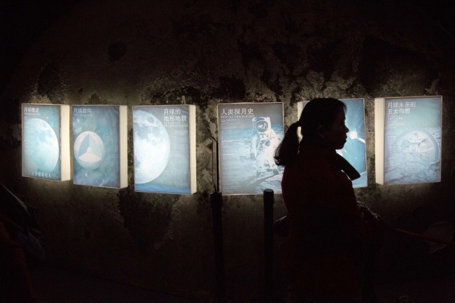 A woman walks past posters during a moon exhibit at the China Science and Technology Museum in Beijing on Sunday. (AP-Yonhap News)