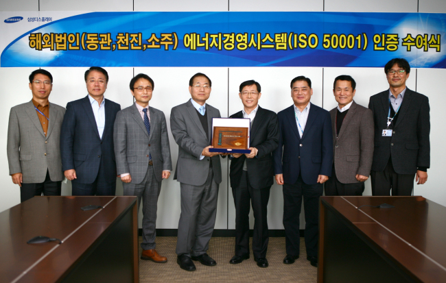 Samsung Display executive vice president Lee Sun-yong (fourth from right) poses with DQS UL Korea managing director Lee Jang-sook (fifth from right) after receiving a declaration of conformance at a ceremony in Asan on Wednesday. The company was certified with the “ISO 50001” ― a standard for superior energy management systems set by the International Organization for Standardization ― at three of its overseas locations in China.(Samsung Display)