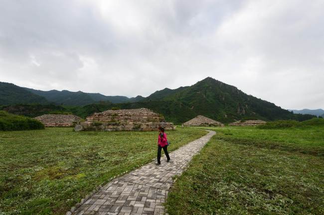 A woman walks past tombs at a heritage park in the Chinese border city of Jian, in northeast China’s Jilin Province. (AFP-Yonhap News)