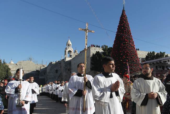 A clergyman holds a crucifix in Manger Square outside the Church of the Nativity as Christians gather for Christmas celebrations in the West Bank city of Bethlehem, on Tuesday. (AFP-Yonhap News)