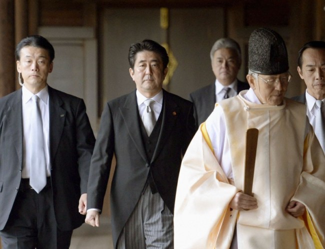 Japan’s Prime Minister Shinzo Abe (center) is led by a Shinto priest as he visits Yasukuni shrine in Tokyo on Thursday. (Yonhap News)