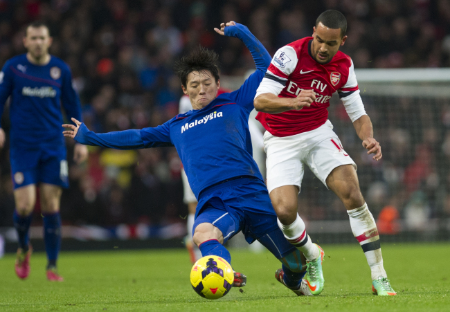 Arsenal’s Theo Walcott (right) fights for the ball with Cardiff City’s Kim Bo-kyung at Emirates Stadium in London on Wednesday. (AP-Yonhap News)