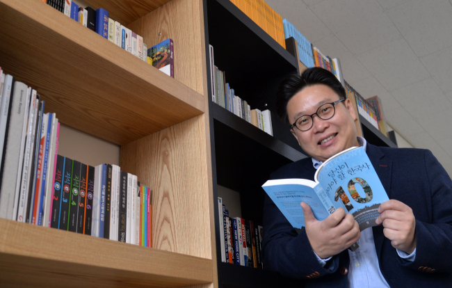 Seo Kyoung-duk poses with a copy of “Ten Moments in Korean History You Should Know” at his office in northern Seoul. (Lee Sang-sub/The Korea Herald)