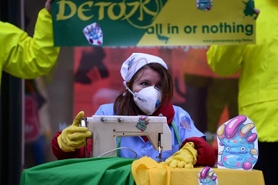 그린피스의 한 활동가가 오염된 옷을 만드는 모습을 따라하고 있다(AFP)