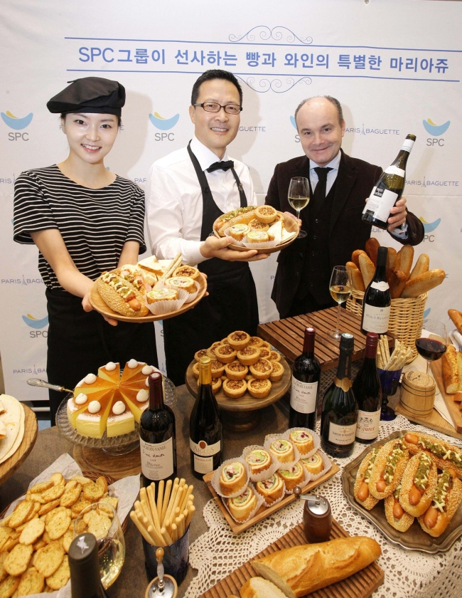 Jung Tae-soo (center), head of Paris Croissant operated by SPC Group, poses Wednesday with French sommelier world champion Olivier Poussier, who was invited to Paris Croissant’s Gwanghwanmun outlet to help customers choose the wine that is most compatible with SPC pastries and desserts. (SPC Group)