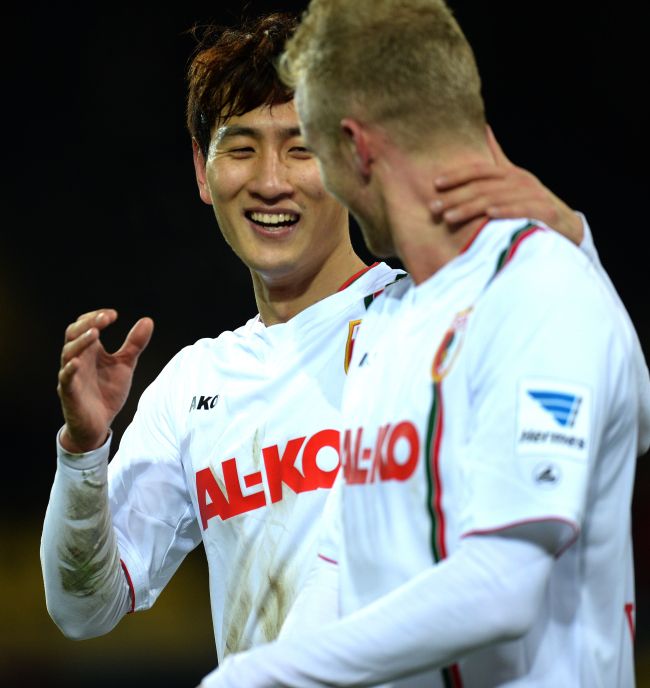 FC Augsburg’s Ji Dong-won celebrates his goal with teammate Andre Hahn on Saturday. (AFP-Yonhap)