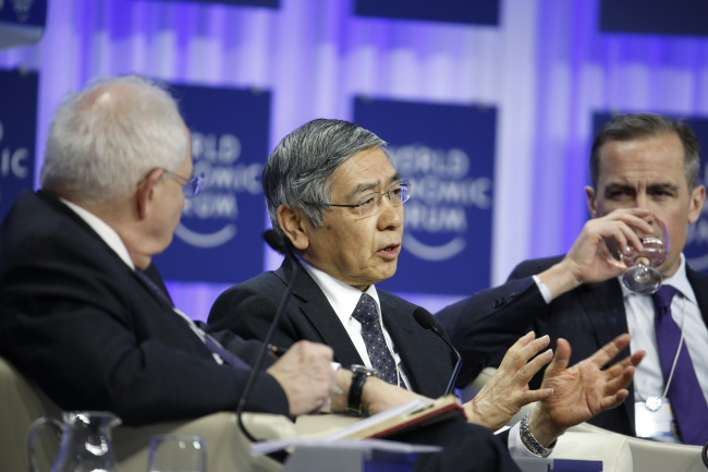 Haruhiko Kuroda (center), governor of the Bank of Japan, speaks as Mark Carney (right), governor of the Bank of England, listens during a panel session on day four of the World Economic Forum in Davos, Switzerland, Saturday. (Bloomberg)