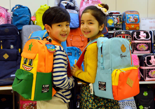 Children model school bags at Emart, where backpacks, indoor slippers and other school-related supplies are on sale to mark the start of a new school year in March. (Yoon Byung-chan/The Korea Herald)