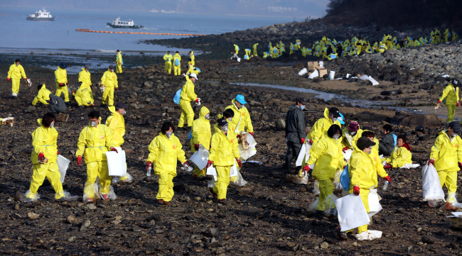 Local residents and officials clean up oil spills in waters near the nation’s southwestern port city of Yeosu on Saturday. (Yonhap)