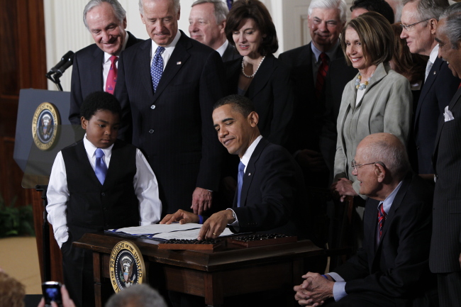 President Barack Obama reaches for a pen to sign the health care bill in the East Room of the White House in Washington on March 23, 2010. (AP-Yonhap)