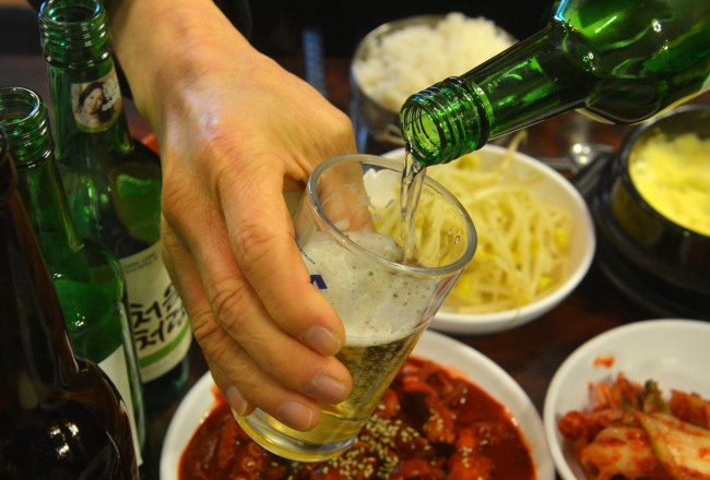 A man pours soju into a beer glass to make somaek, a popular local cocktail. (Korea Herald file photo)