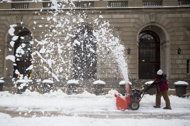 A worker uses a snow blower outside the Internal Revenue Service in Washington, D.C., Thursday. (Bloomberg)