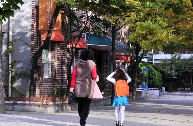 A mother walks with her child to drop her off at a school in Seoul. (Korea Herald file photo)