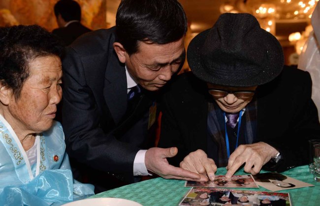 South Korean Kim Se-rin (right), 85, looks at pictures of his family members in North Korea with his sister and cousin during the family reunions held at the Mount Geumgangsan resort on Thursday. (Park Hae-mook and Joint Press Corps)