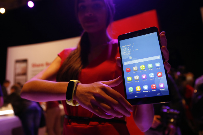 An employee displays a MediaPad X1 tablet and TalkBand wearable device during a Huawei Technologies news conference ahead of the Mobile World Congress in Barcelona, Spain, Sunday. (Bloomberg)