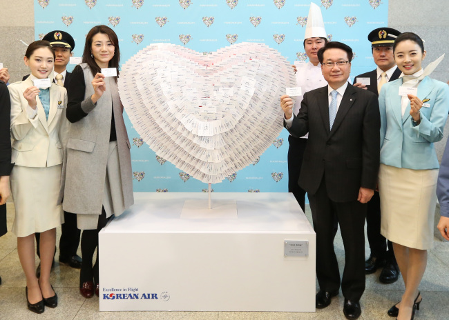 Korean Air CEO Ji Chang-hoon (third from right) and communications chief Cho Hyun-min (third from left) pose with a heart-shaped sculpture made of the business cards of some 1,200 employees during a New Year event at the company’s headquarters in central Seoul on Monday. (Korean Air)