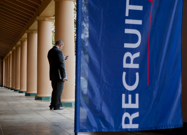 A job seeker checks his mobile phone outside of a job fair in San Diego, California, Feb. 27. (Bloomberg)