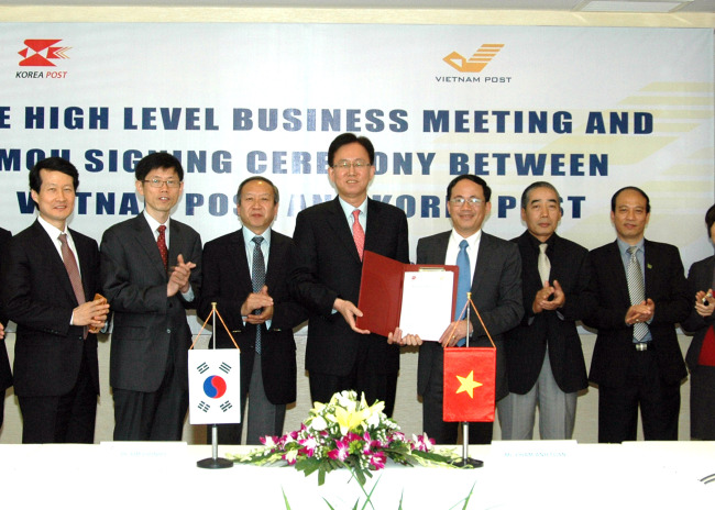 Korea Post president Kim Joon-ho (fourth from left) and Pham Anh Tuan (third from right), president and CEO of Vietnam Post, pose with executives after signing a memorandum of understanding to strengthen ties between the two postal services in Hanoi, Vietnam, Tuesday. (Korea Post)