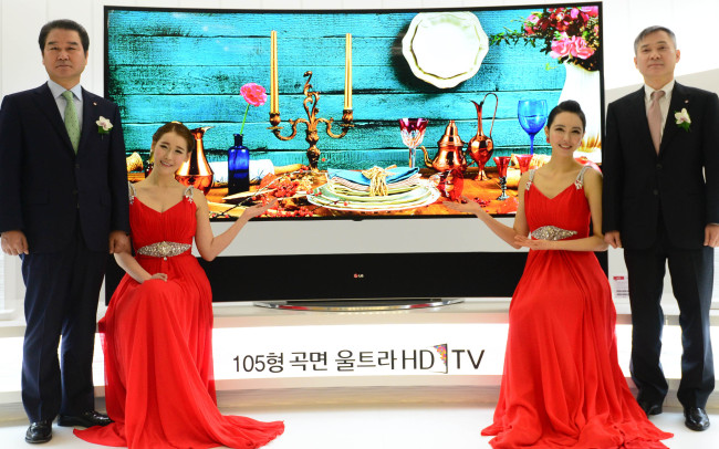 Choi Sang-gyu (left), head of Korea sales and marketing at LG Electronics, and Ha Hyun-hwoi (right), president of home entertainment, pose Tuesday with the company’s expanded lineup of ultrahigh-definition televisions. (Lee Sang-sub/The Korea Herald)