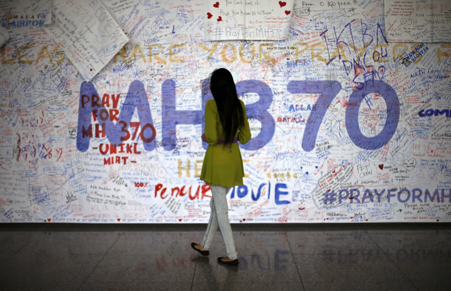 A woman reads messages and well wishes to people involved with the missing Malaysia Airlines jetliner MH370, Saturday, in Sepang, Malaysia. (AP-Yonhap)