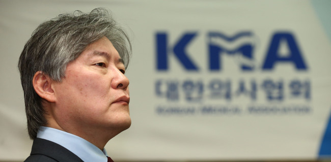 Korean Medical Association head Roh Hwan-kyu listens to an announcement on the deal made between the KMA and the government over new medical policies on Monday. (Yonhap)