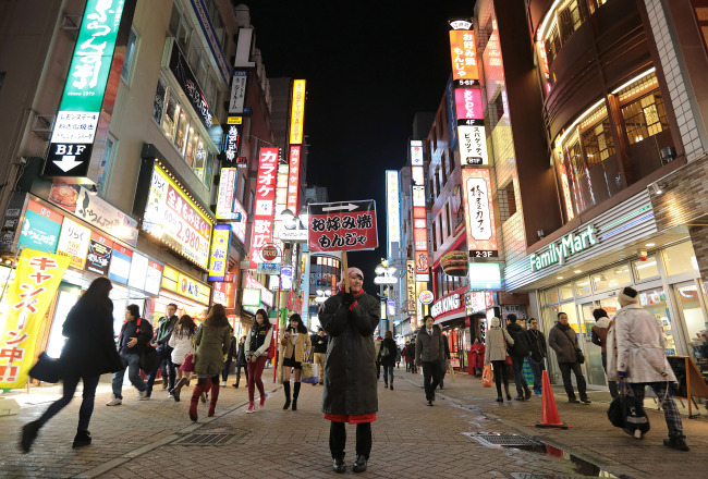 An employee holds a sign for an “okonomiyaki” restaurant in the Shibuya district of Tokyo. (Bloomberg)