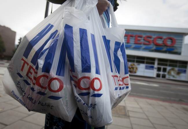 A customer carries Tesco shopping bags as she leaves one of the company’s stores in London. (Bloomberg)