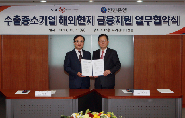 Seo Jin-won (right), Shinhan Bank president, poses with Park Cheol-kyu, president of the Small and Medium Business Corporation after signing an agreement to provide financial services to SMEs operating overseas at SBC’s headquarters in Seoul in December 2013. (Shinhan Bank)