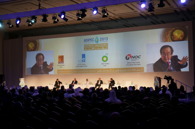 Korea National Oil Corp. CEO Suh Moon-kyu (right and on the main screen) delivers a speech at the 2013 Abu Dhabi International Petroleum Exhibition and Conference. (KNOC)