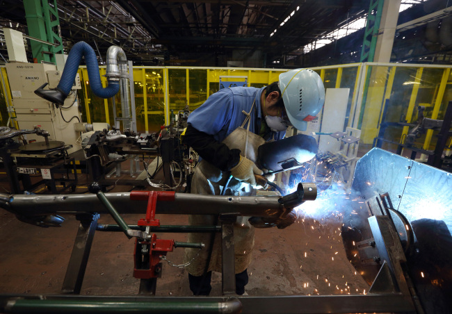 A worker welds an automobile part in the chassis manufacturing department at a Toyota Motor Corp. plant in Toyota City, Japan, Feb. 25. (Bloomberg)