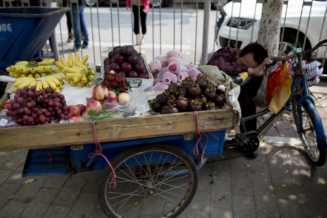 A fruit vendor leans against a bicycle as he sleeps in the Zhujiang New Town district of Guangzhou, Guangdong province, China. (Bloomberg)