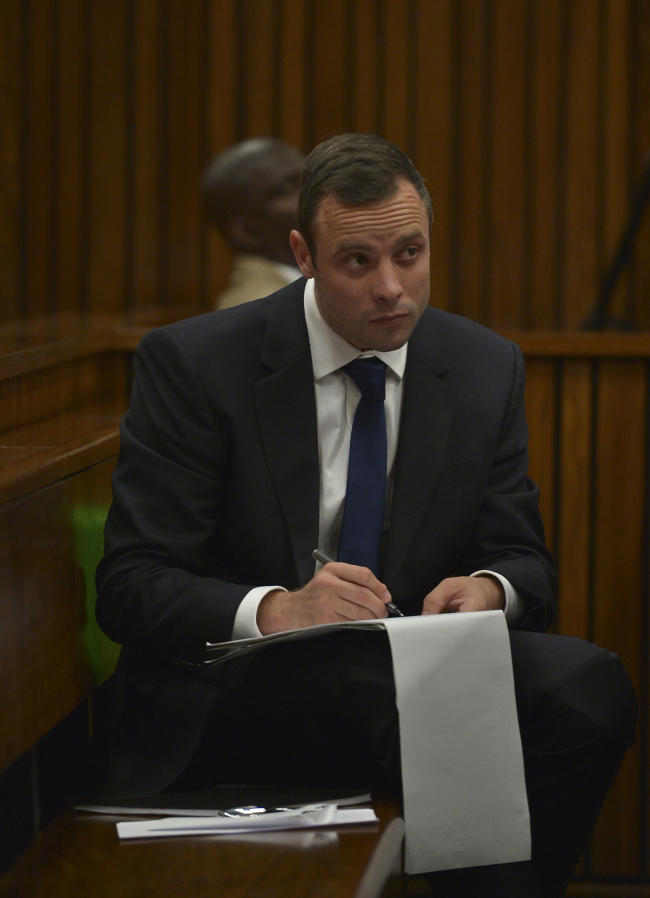 Oscar Pistorius makes notes as he sits in the dock listening to cross questioning about the events surrounding the shooting death of his girlfriend Reeva Steenkamp, in court during the second week of his trial in Pretoria, South Africa, on March 12, 2014. Pistorius is charged with the shooting death of Steenkamp, on Valentines Day in 2013. (AP-Yonhap)